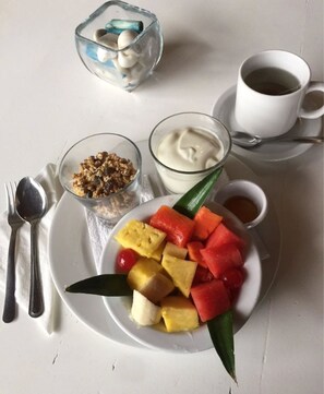 Un plato de desayuno con fruta, yogur y granola.