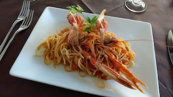 Un plato de espagueti con patas de cangrejo sobre un plato blanco.