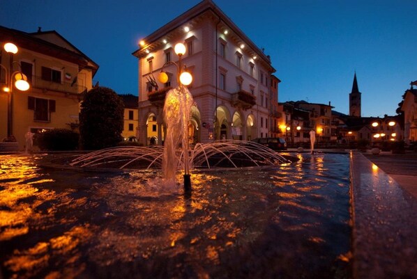 A fountain in a square with buildings in the background.