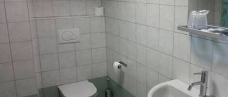 Un baño pequeño con inodoro, lavamanos y espejo.