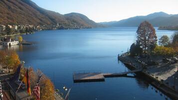 A calm lake with a dock and a bridge, surrounded by hills and autumn trees.