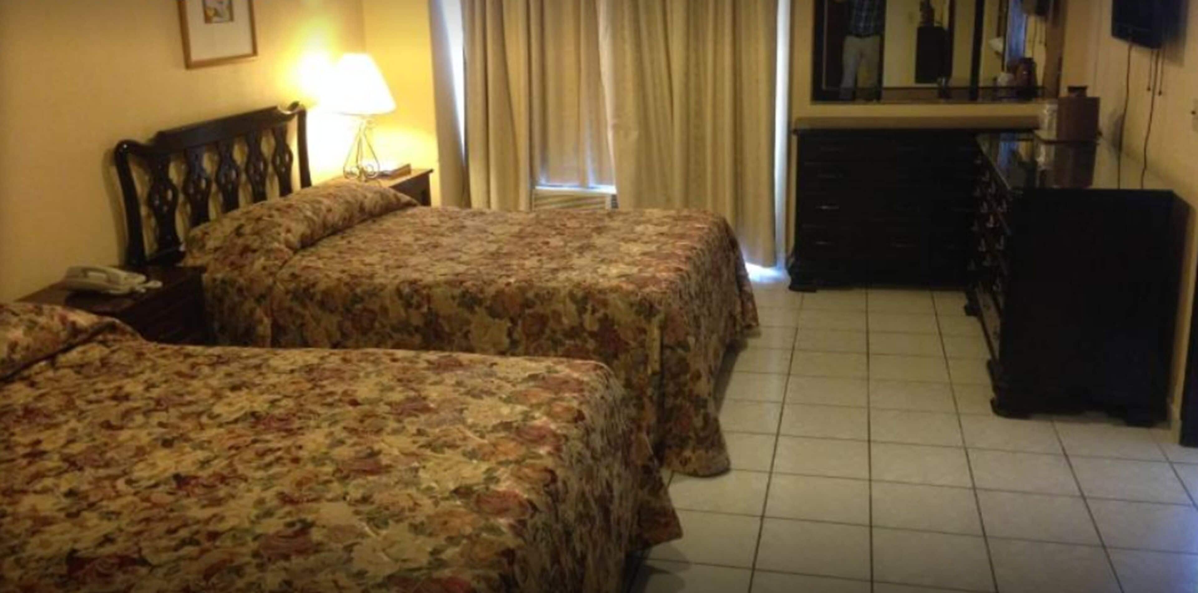 Una habitación de hotel con dos camas, un escritorio, una silla, un aparador y un televisor.