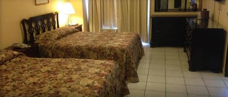 Una habitación de hotel con dos camas, un escritorio, una silla, un aparador y un televisor.