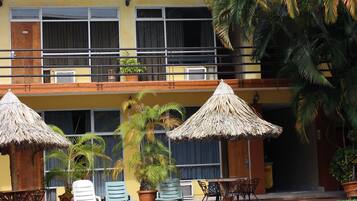 A hotel with a swimming pool, outdoor seating, and palm trees.