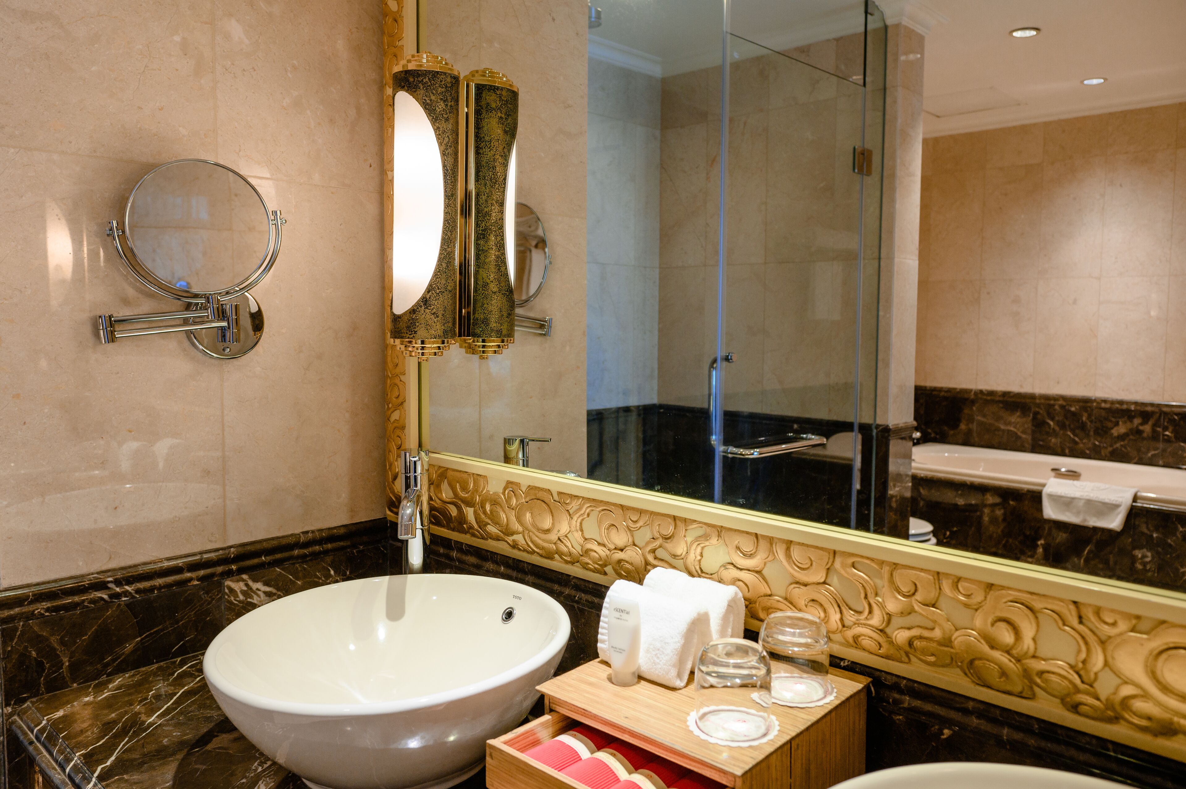 A bathroom with a large oval sink, a round mirror, and a glass-enclosed shower.