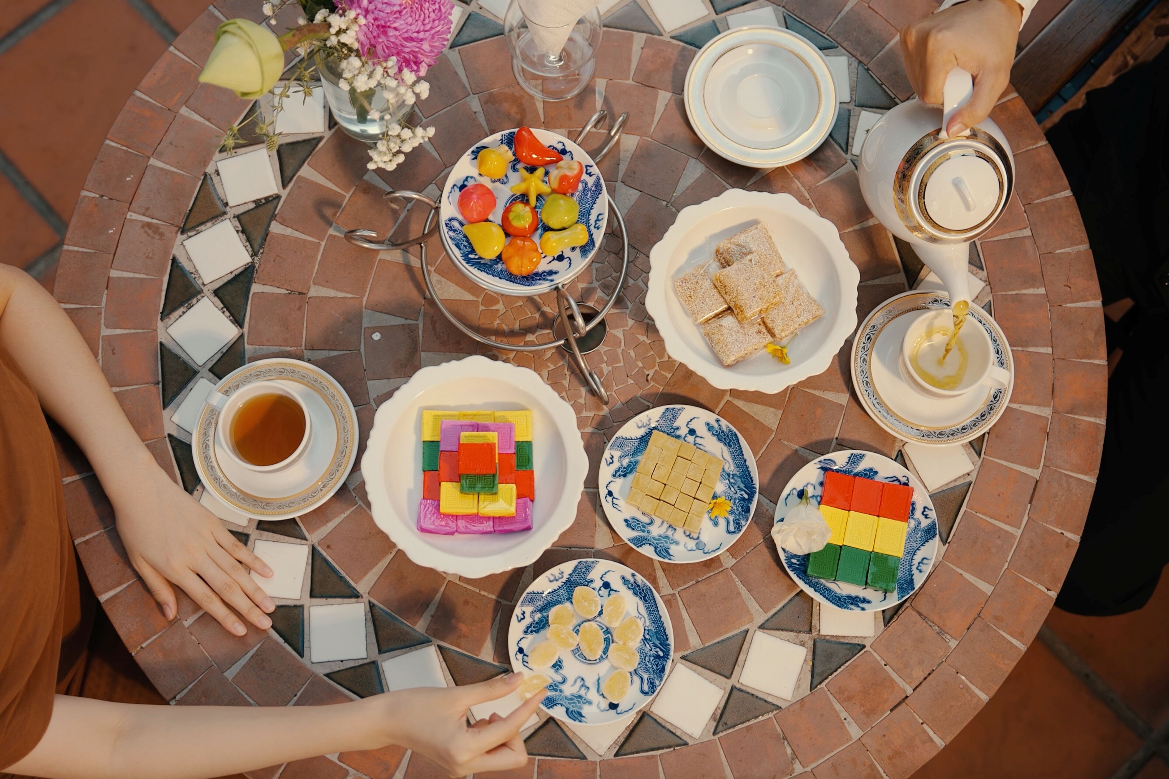A round table with various food items and drinks, surrounded by people.
