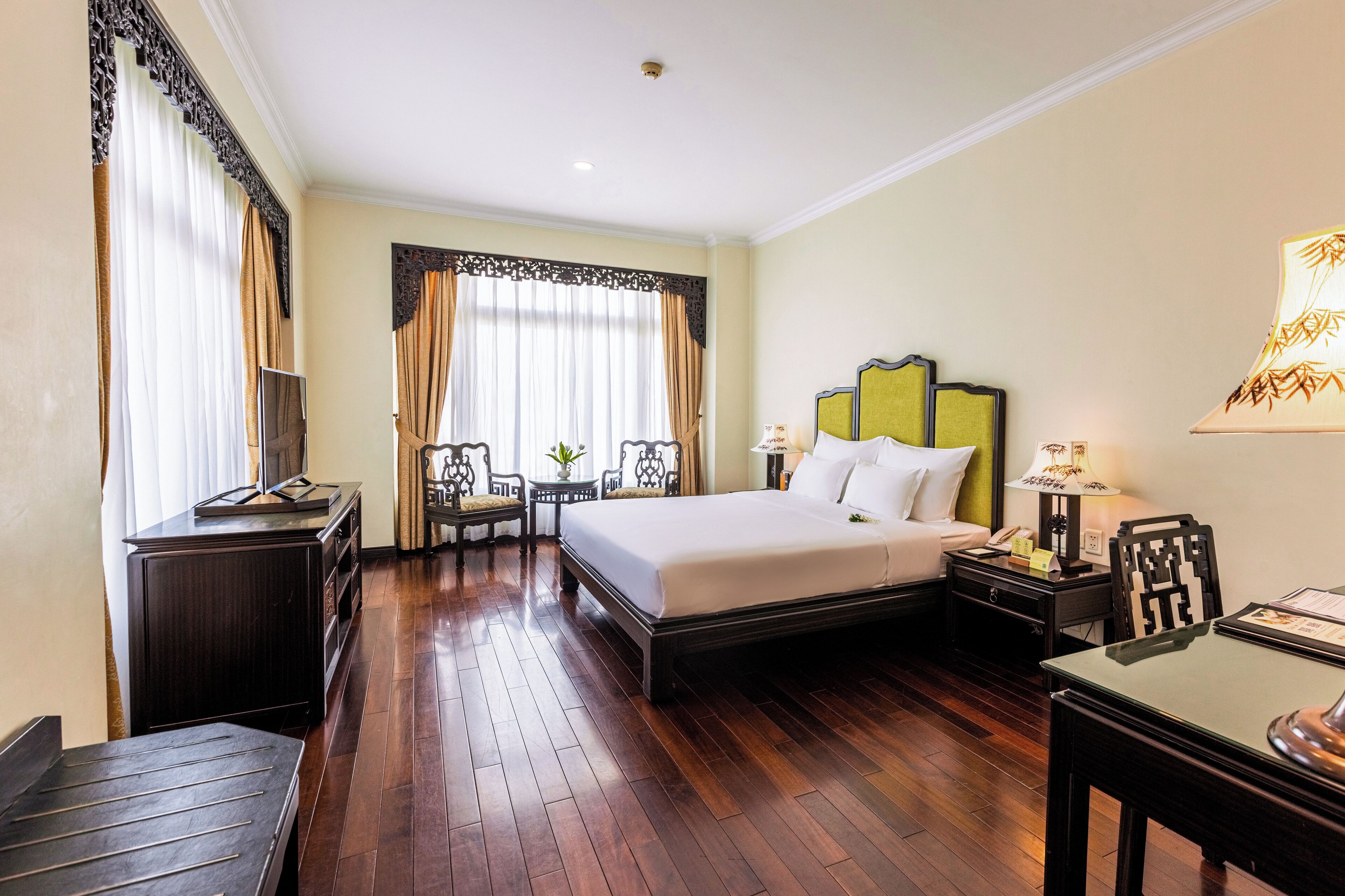 A hotel room with a large bed, bedside tables, a desk, and a chair.