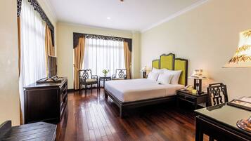 A hotel room with a large bed, bedside tables, a desk, and a chair.