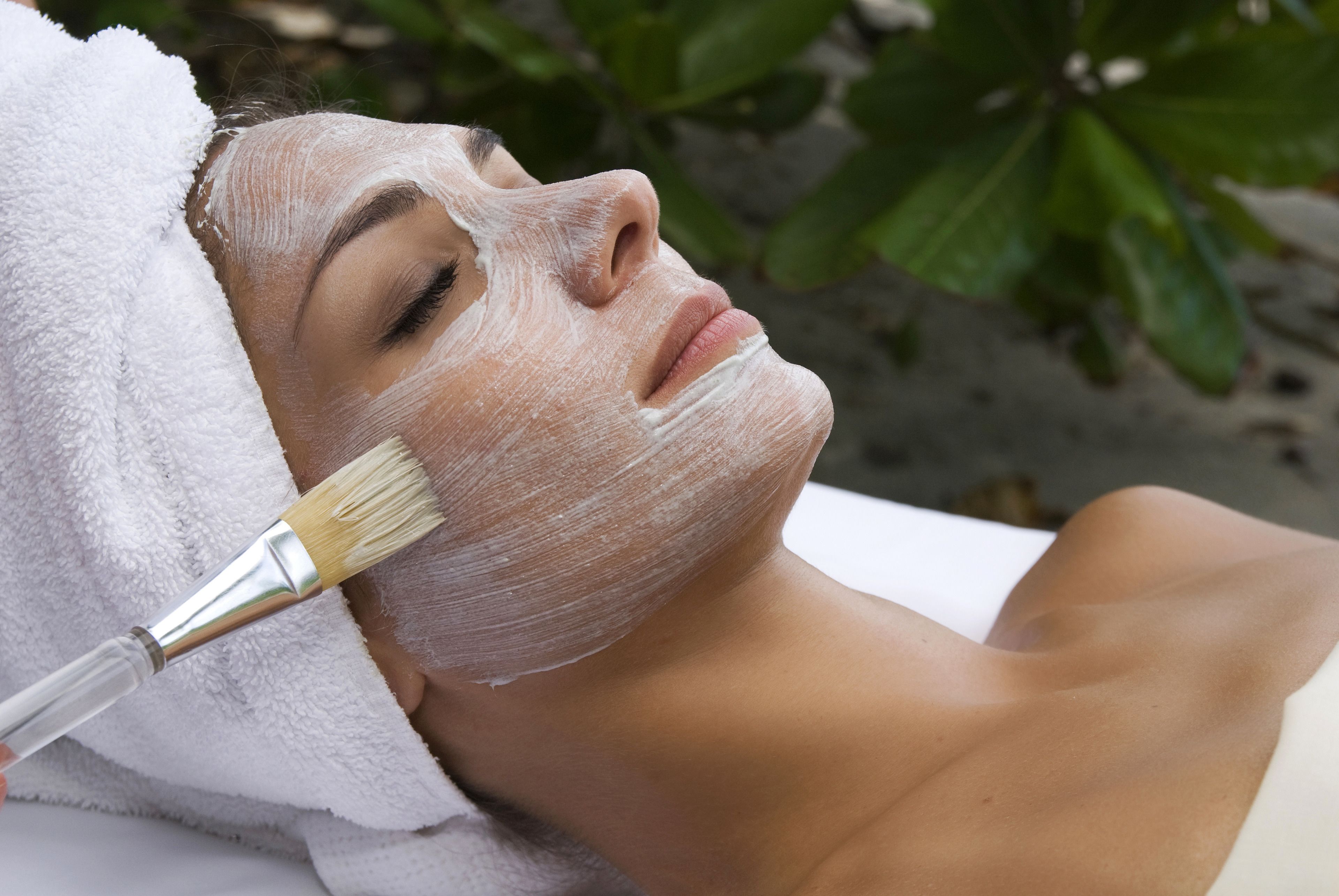 A person receiving a facial treatment with a brush.