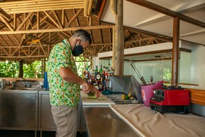 A chef preparing food in a kitchen with stainless steel appliances and a wooden ceiling.