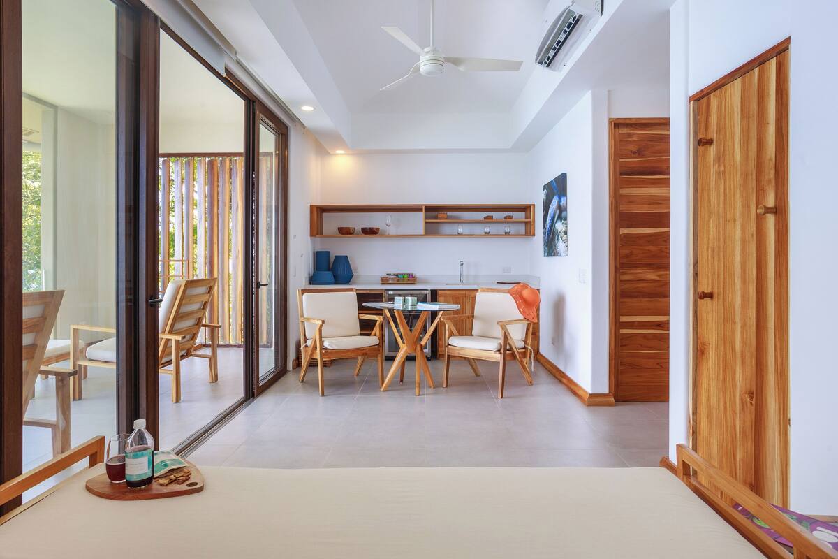 A modern kitchen with a dining area, wooden furniture, and a large sliding glass door leading to an outdoor space.