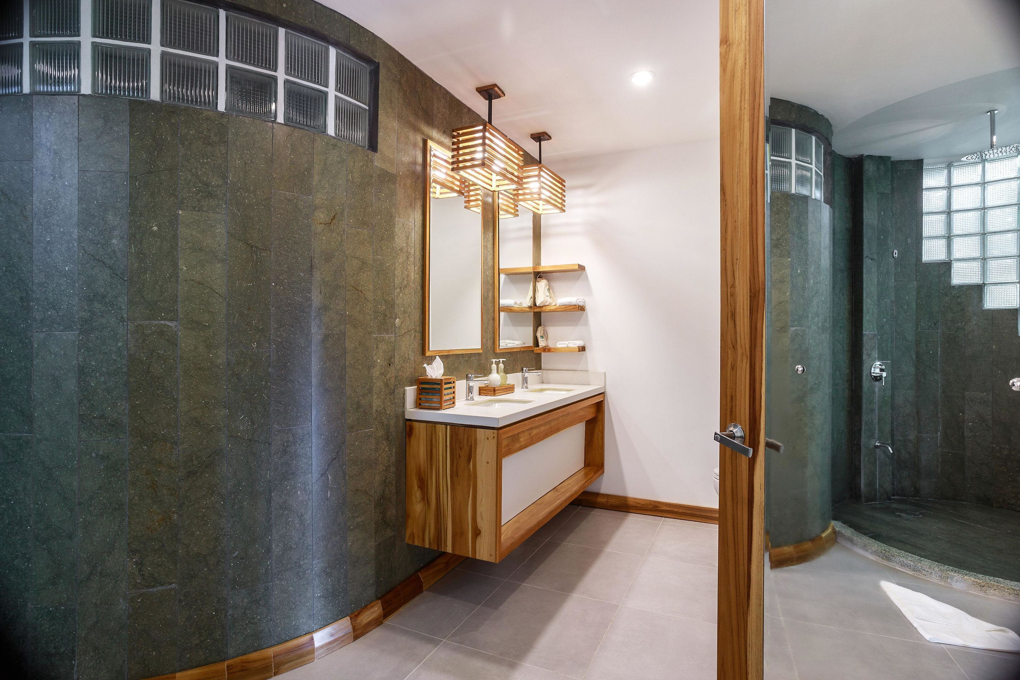 A modern bathroom with a wooden vanity, a glass shower enclosure, and a large mirror.