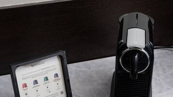 A Nespresso coffee machine with a box containing two capsules and a spoon.