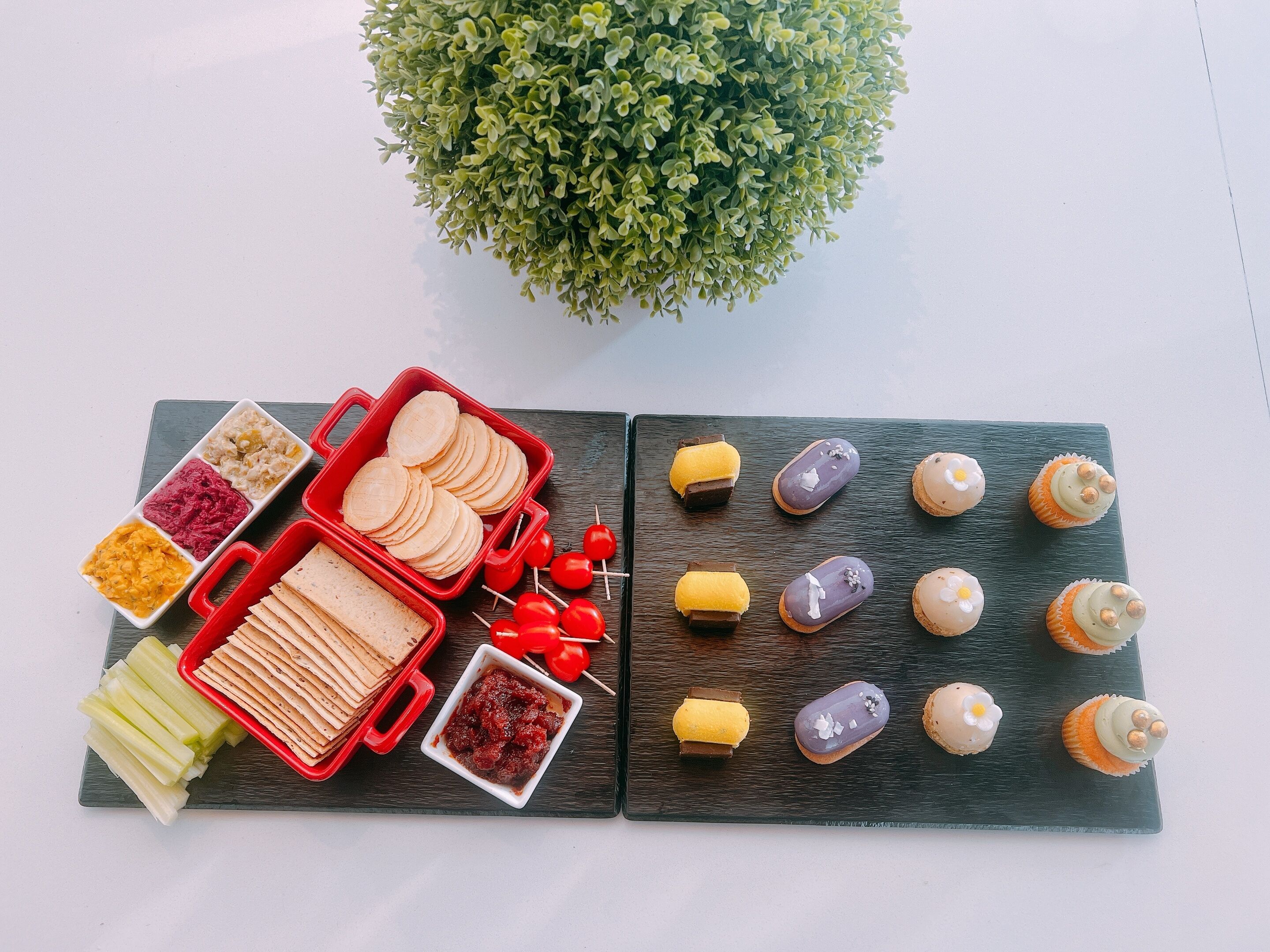 A variety of food items arranged on a wooden board, including flatbreads, dips, and decorated pastries.
