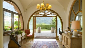 Une pièce dotée d’une grande porte en arc de cercle, d’un lustre, d’une armoire en bois et d’un tapis.