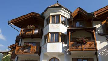 Un hôtel doté d’une tour d’angle, de balcons en bois ornés de jardinières fleuries et d’une enseigne indiquant : « Du Lac Vital Mountain Hotel ».