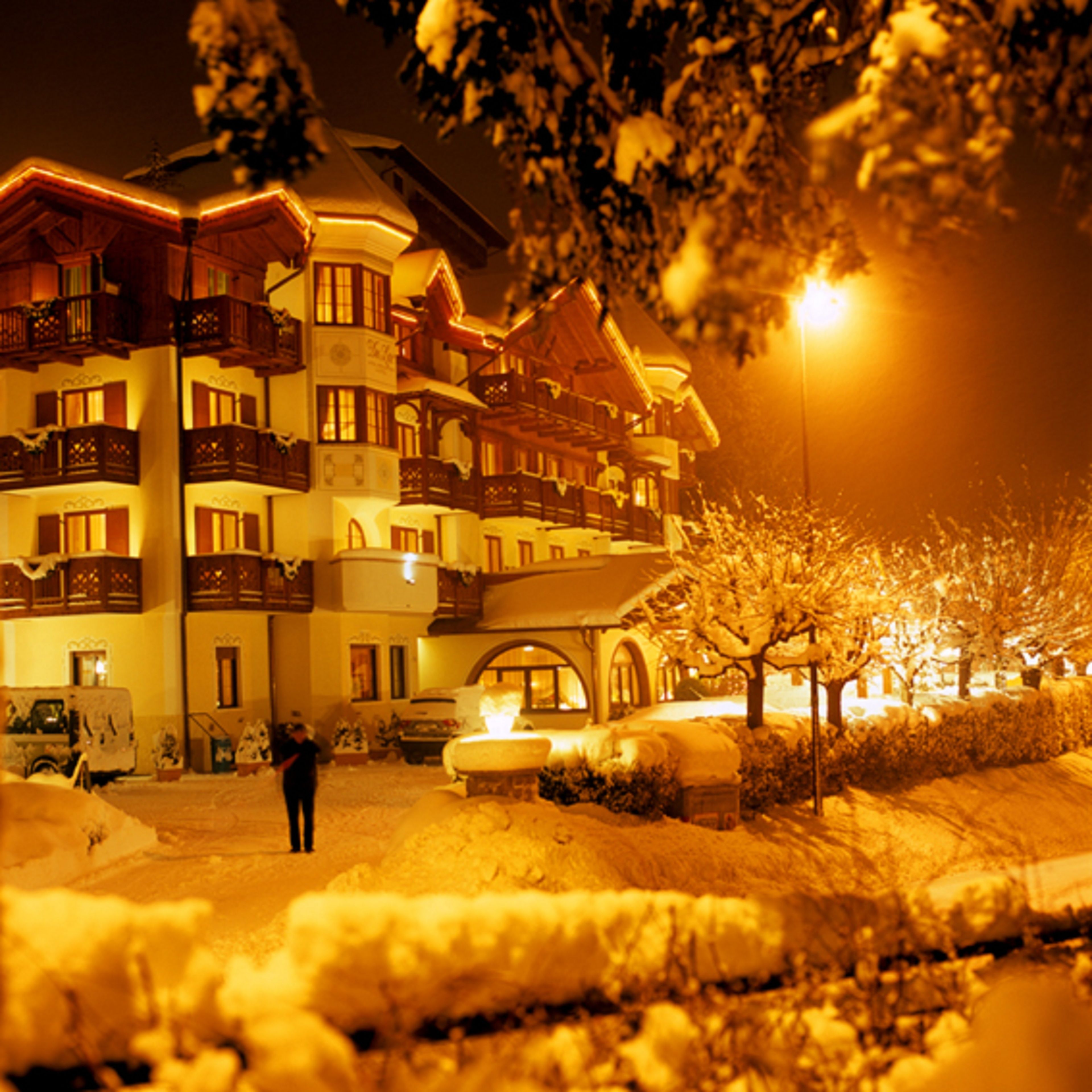 A snow-covered building with multiple balconies and a person standing in front.