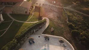 An aerial view of a coastal property with a swimming pool, lounge chairs, and a stone building. - Hotel Relais Valkarana (Sant'Antonio di Gallura)