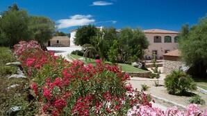 Eine Villa mit Garten, einem Kiesweg und einem strahlend blauen Himmel.