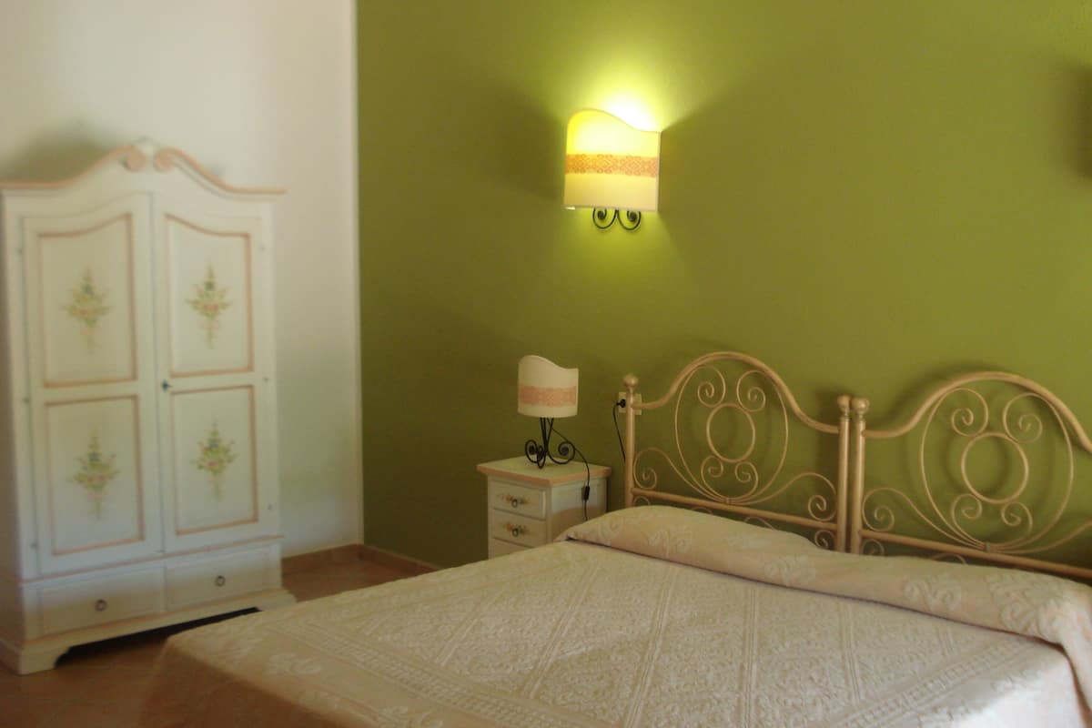 Ein Schlafzimmer mit Bett, Nachttisch, Lampe und Kleiderschrank.