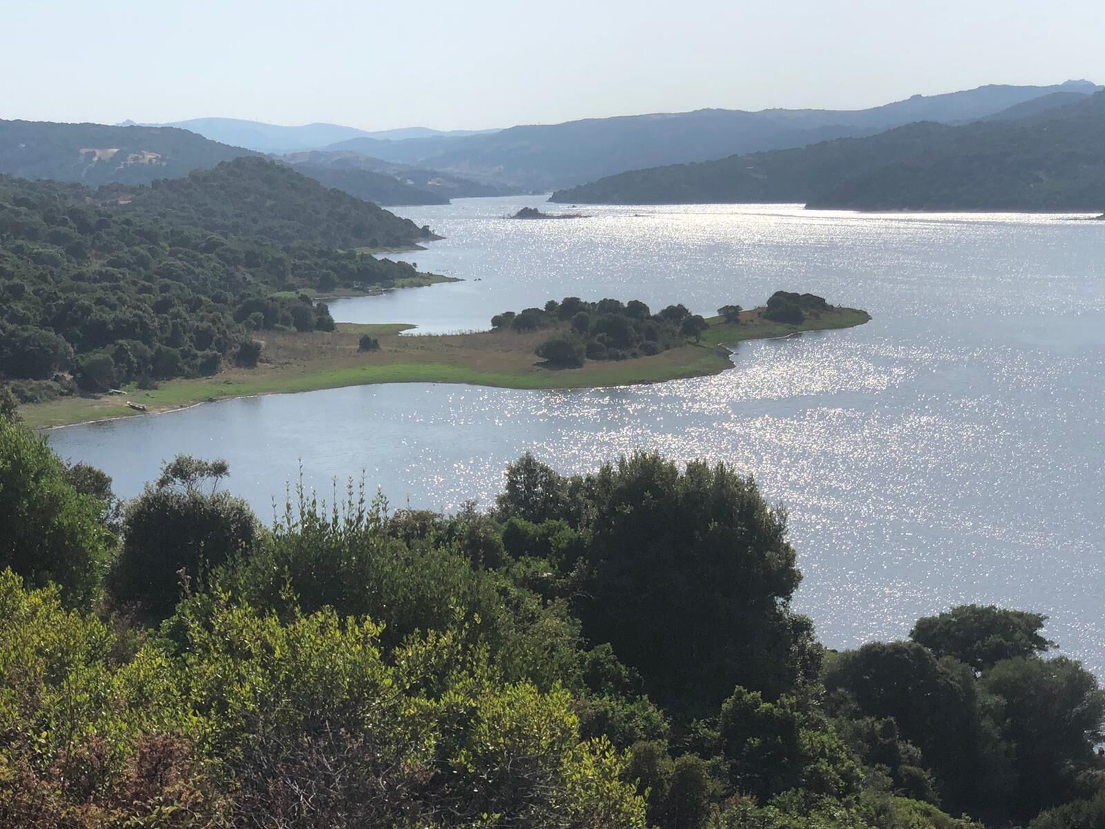 A lake surrounded by hills and dense greenery.