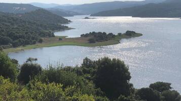 A lake surrounded by hills and dense greenery.
