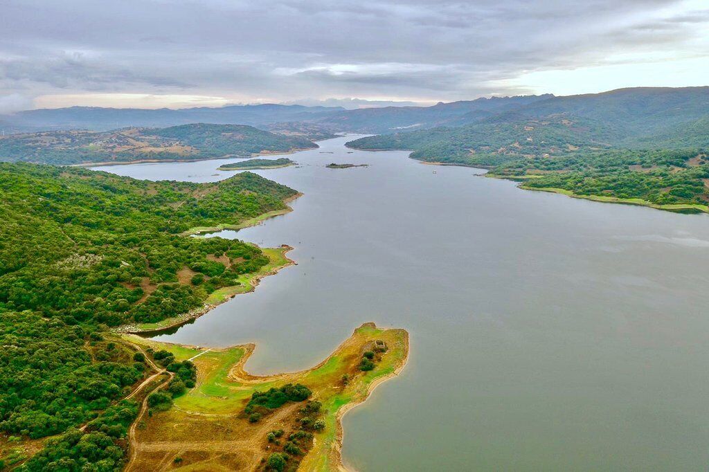 Une vue aérienne d’une rivière serpentant à travers un paysage verdoyant, avec des collines en arrière-plan.