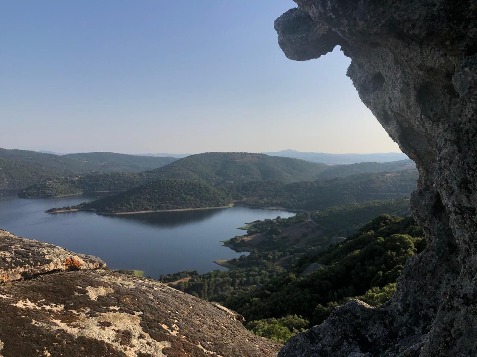 Un lago rodeado de colinas con un promontorio rocoso en primer plano.