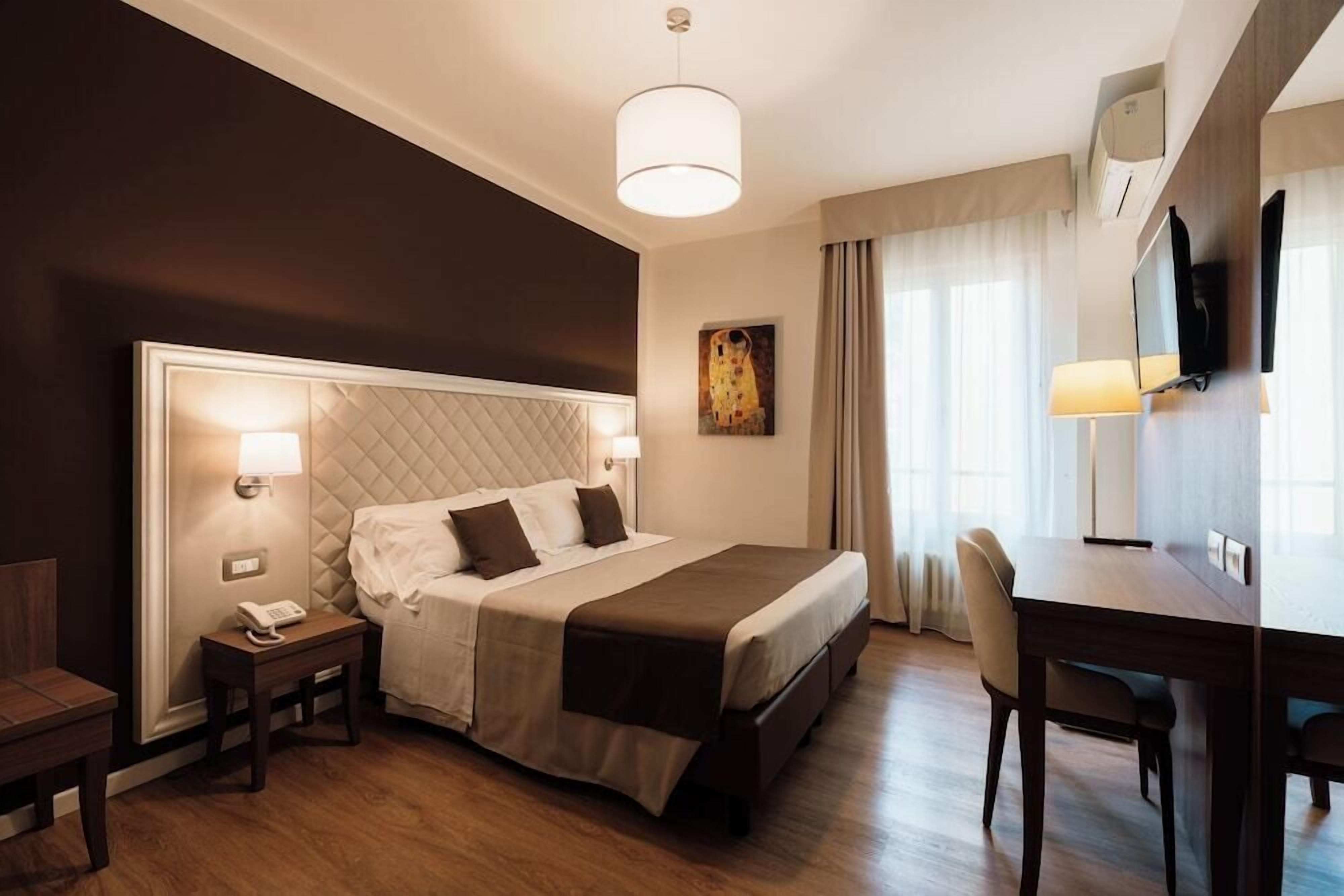 Ein Hotelzimmer mit einem großen Bett, Nachttischlampen, einem Schreibtisch und einem Sessel.