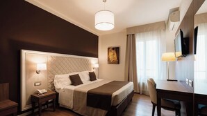 A hotel room with a large bed, bedside lamps, a desk, and a chair. - Eden (Salo)