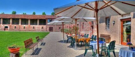 Un patio al aire libre con mesas y sillas, sombrillas y un edificio de ladrillo al fondo.