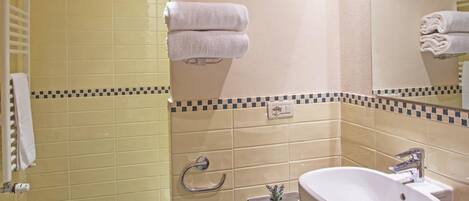 A modern bathroom with a large sink, a mirror, and a shower area.