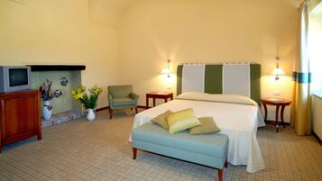 Ein Hotelzimmer mit Bett, Fernseher, Sessel, Nachttisch und Lampe.