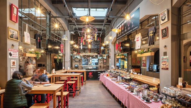 A restaurant with high ceilings, exposed beams, and a central serving area. - Hotel Palác U Kočků by Adrez Living (Prague)