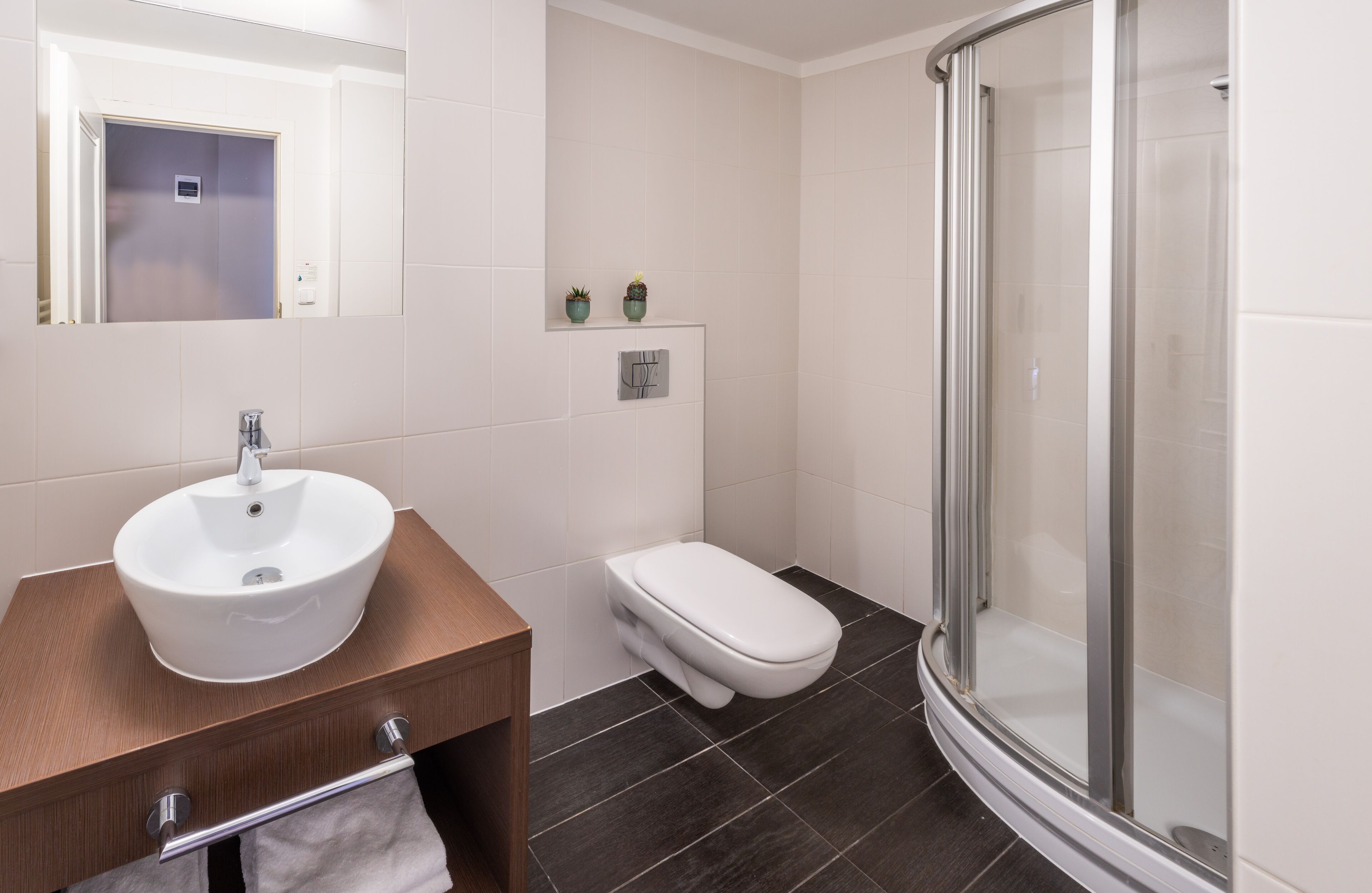 Un baño moderno con lavamanos, inodoro y cabina de ducha de vidrio.