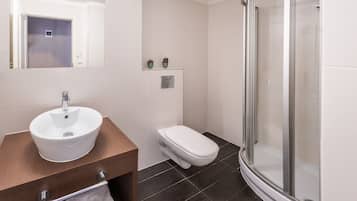 A modern bathroom with a white sink, toilet, and glass shower enclosure.