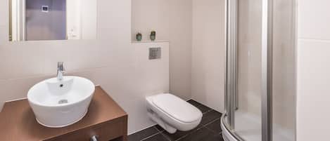 Un baño moderno con lavamanos, inodoro y cabina de ducha de vidrio.