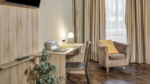 A modern room with a wooden desk, a laptop, a glass of red wine, a lamp, a chair, and a television mounted on the wall. - Hotel Palác U Kočků by Adrez Living (Prague)