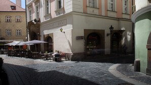 A historic building with a pink facade, multiple windows, and a ground-level entrance with outdoor seating.