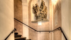 A staircase with a stone sculpture of a historical scene. - Hotel Palác U Kočků by Adrez Living (Prague)