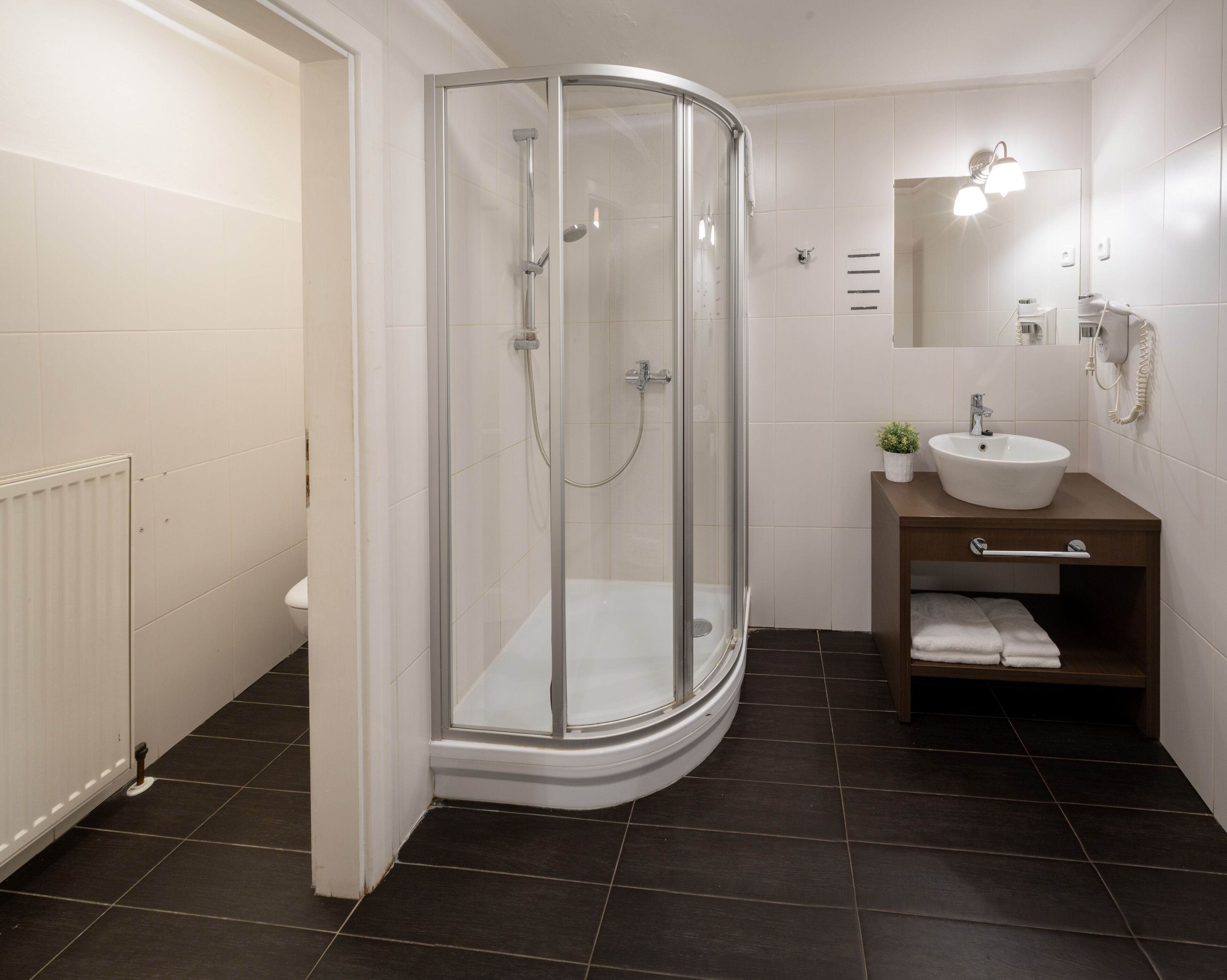 A modern bathroom with a glass-enclosed shower, a white sink, and a wooden vanity.