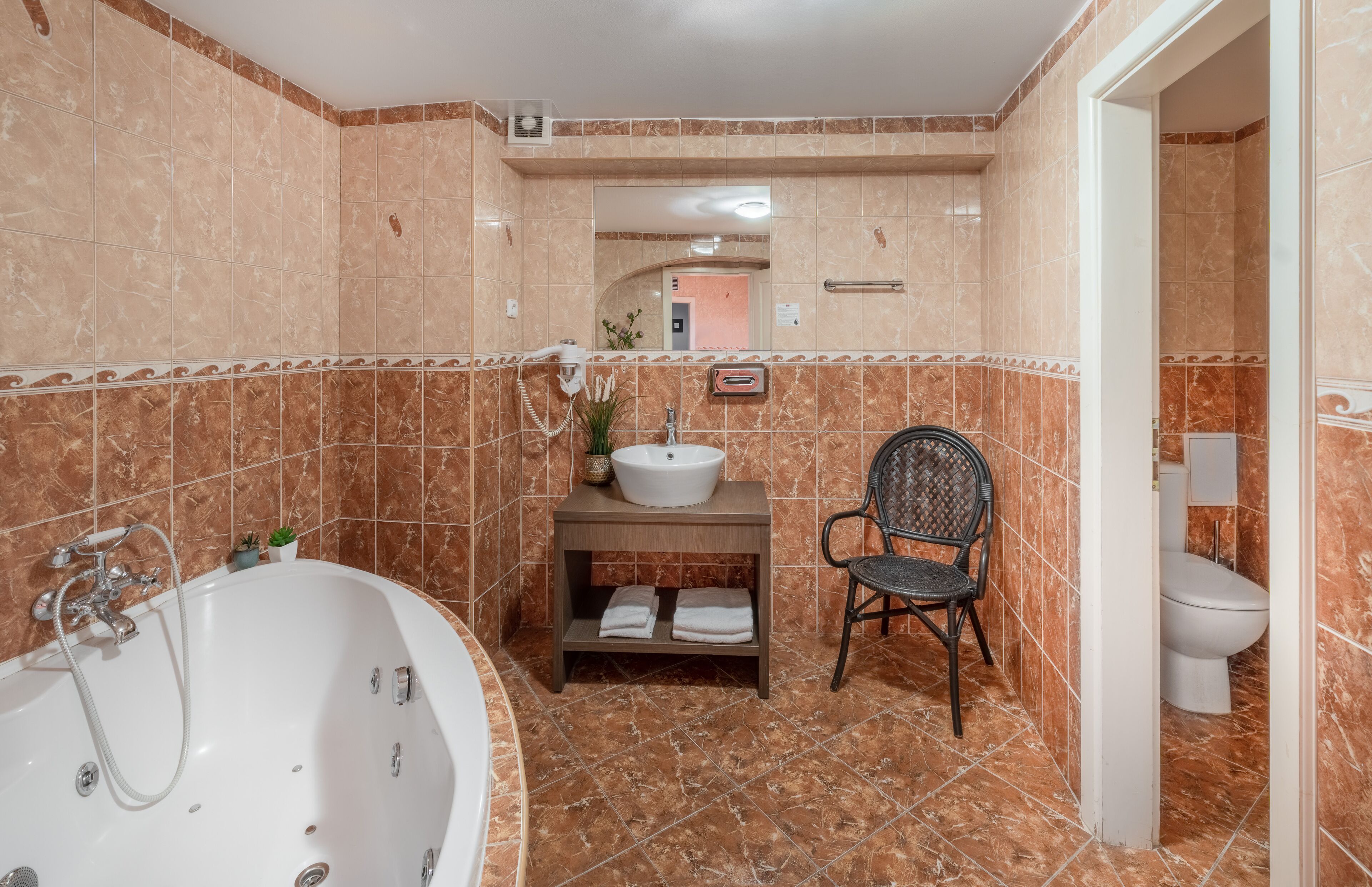 Une salle de bain avec une baignoire, un lavabo, une chaise et des toilettes.