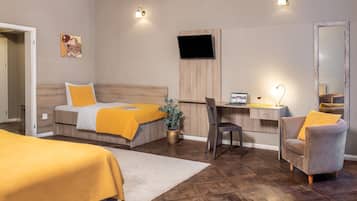Habitación de hotel con dos camas, un escritorio con una computadora portátil, una silla, un espejo y una planta en maceta.