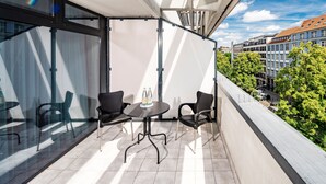 A balcony with a table and chairs, a glass partition, and a view of buildings and trees. -  Hotel Chateau Kurfürstendamm (Berlin)