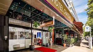 A hotel entrance with a red carpet, potted plants, and a sign reading 'HOTEL CHATEAU.' -  Hotel Chateau Kurfürstendamm (Berlin)