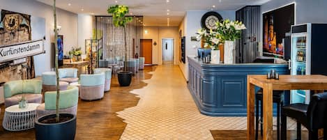 A hotel lobby with seating areas, a reception desk, and a large clock.