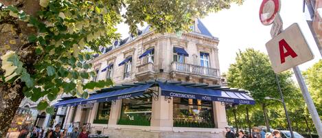 A historic building with a restaurant and lounge on the ground floor, featuring outdoor seating and a classic architectural style.