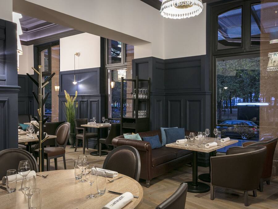 Un restaurante con una zona de estar acogedora, un bar y un amplio ventanal con vistas a la ciudad.