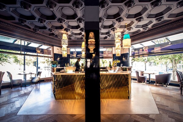 A modern bar area with a central bar counter, seating around, and a decorative ceiling.