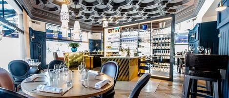 A restaurant with a bar area, wooden tables, and chairs.